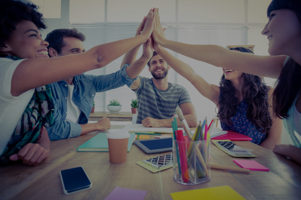 Cinco jóvenes chocando las manos en señal de celebración y trabajo en equipo